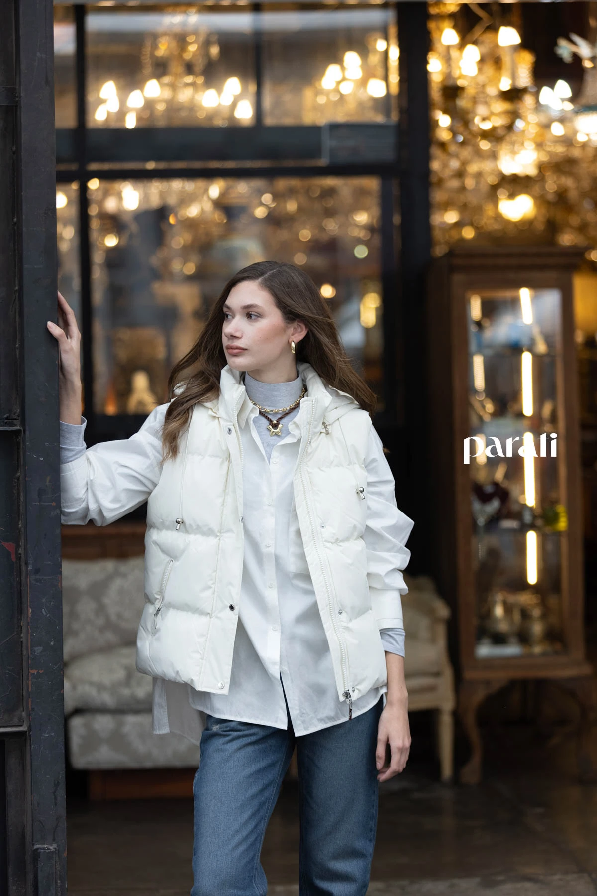 Chaleco puffer blanco @perramusoficial, camisa blanca oversize @mishkabuenosaires, polera de algodón gris @boliviauniverso, jean recto azul @hausofdnm, collares cadena y cordón con dije, y aros argolla dorada @ritace.accesorios, zapatillas combinadas y medias @lecoqsportif_ar.