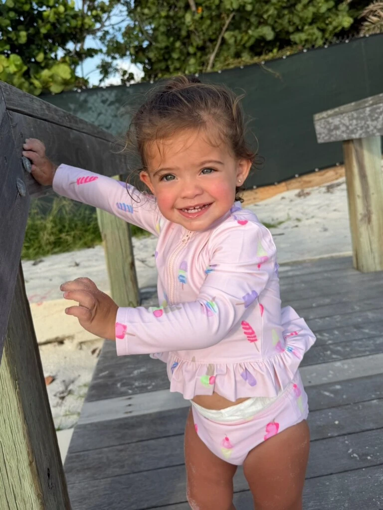 Olivia llevó una malla de mangas largas con protección UV en color rosa pastel, decorada con un estampado de pequeños helados y dibujos multicolores.