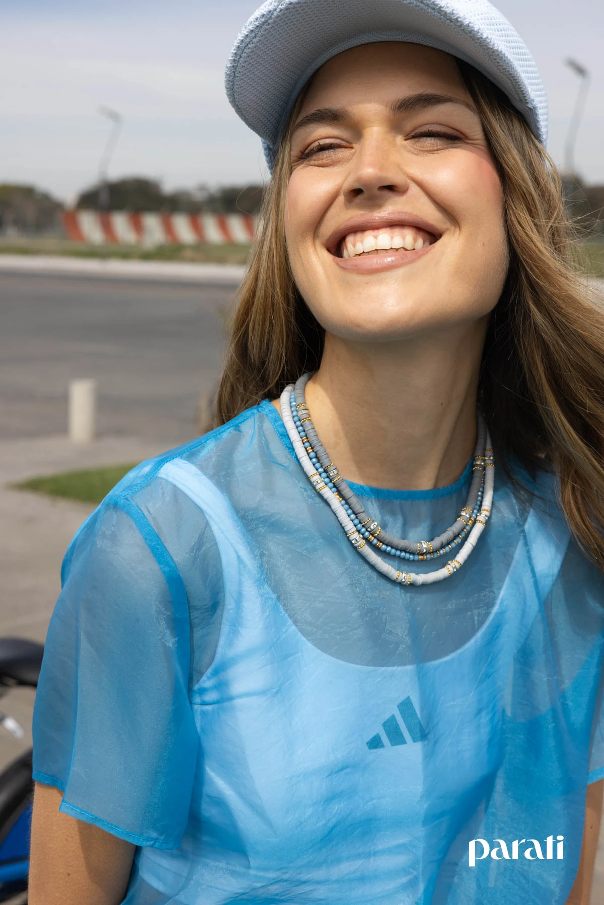 Blusa de organza de @laspepasinst, top deportivo de @adidasar, pantalón sastrero de @wearelse_, pañuelo plisado anudado a la cintura de @laspepasinst, cap celeste de @adidasar, mix de collares de @luliobligado.accesorios, neceser rayado de @ayfidela y zapatillas Samba azules de @adidasar.