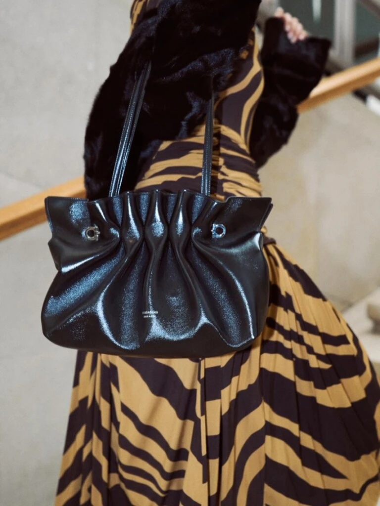 La modelo completó el look con una cartera pequeña y estructurada de Ferragamo en cuero negro.